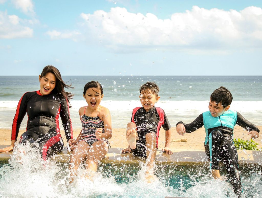 Eine Familie vergnügt sich beim Planschen im Wasser an einem sonnigen Tag in Bali, Indonesien.